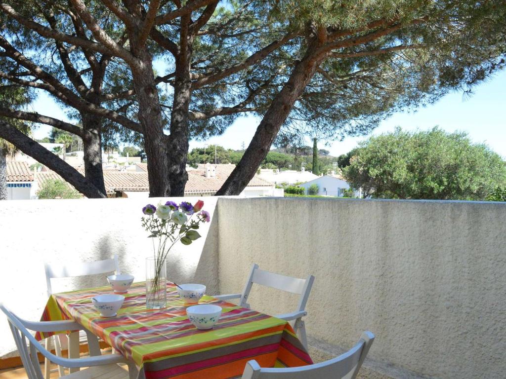 une table avec des chaises et un vase de fleurs dessus dans l'établissement Appartement moderne avec terrasse à 1500m de la plage, parking privé, lave-linge, 4 couchages - FR-1-249-177, au Cap d'Agde