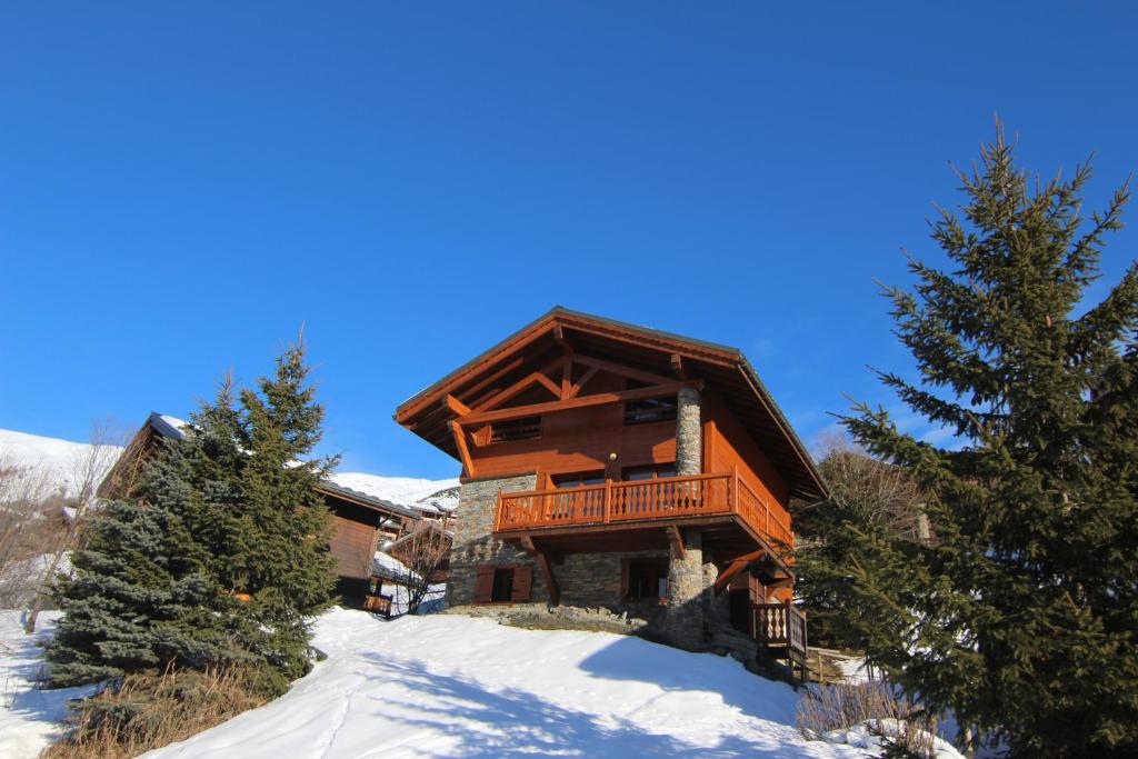 a large log cabin in the snow with trees at Chalet Le Panicaut in Levassaix