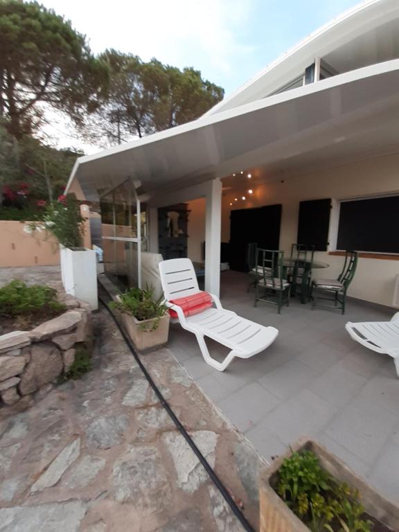 a patio with two white chairs and a table at Vermentinu T1 bis 50 m plage du Ruppione in Pietrosella