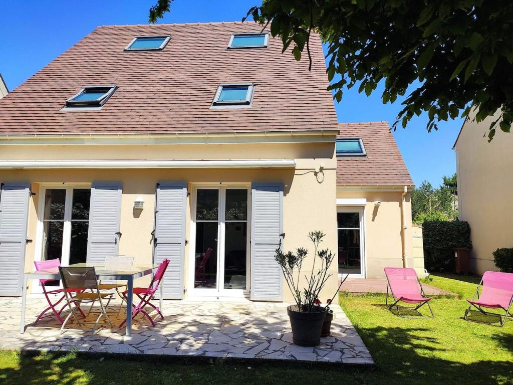une maison avec des chaises roses et une table dans la cour dans l'établissement Villa Chic and Cosy near Versailles, à Bois-dʼArcy