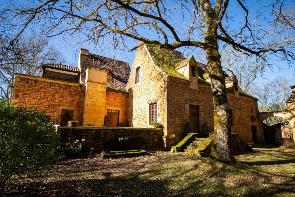 a large brick house with a tree in front of it at Château Les Fournels in Villefranche-du-Périgord