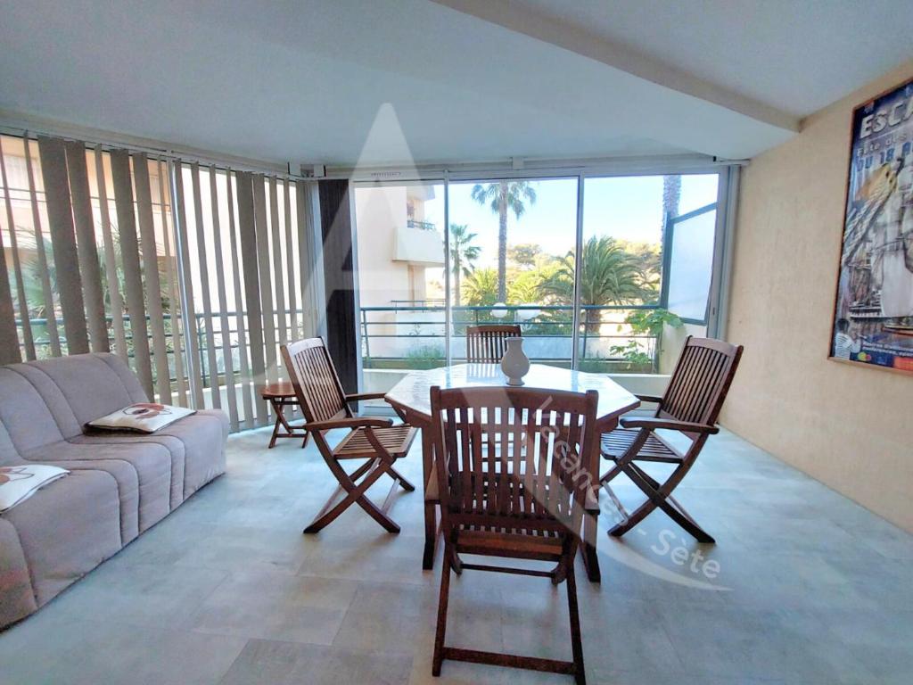 un salon avec un canapé, une table et des chaises dans l'établissement Proche des plages, residence avec piscine, T2 equipe wifi avec garage, à Sète