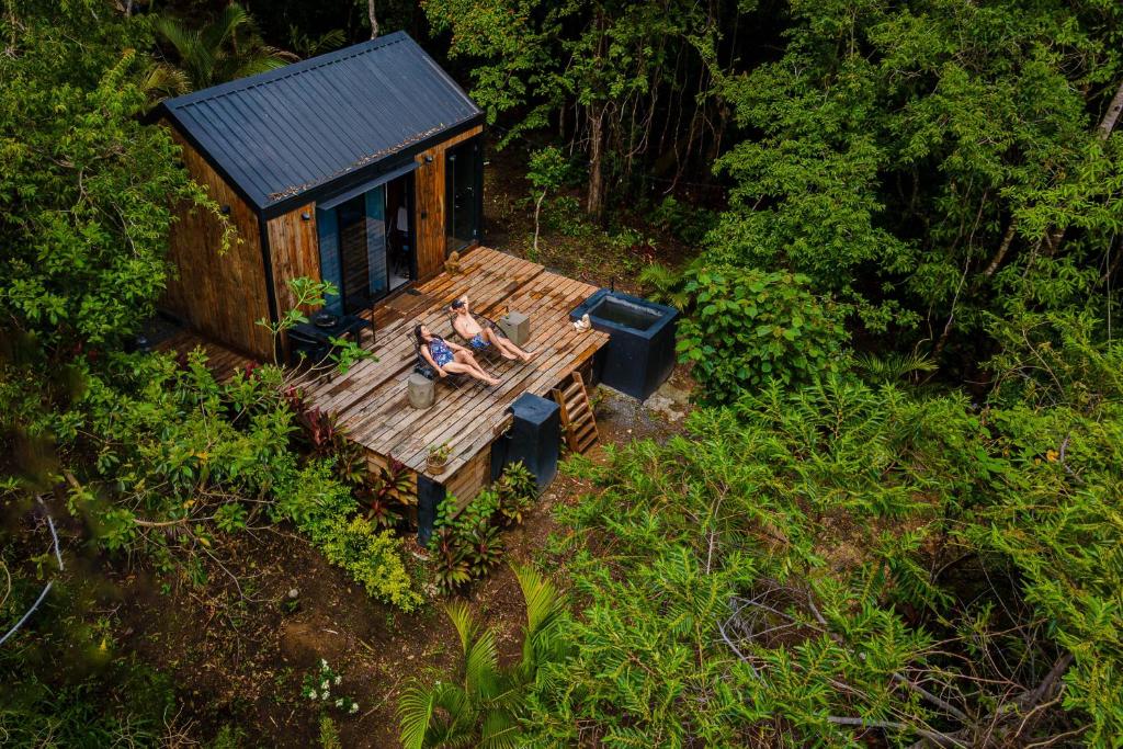 a man sitting on a bench in front of a tiny house at Kooteja Ëra Exclusive Mountain Cabin with Views in Las Colinas