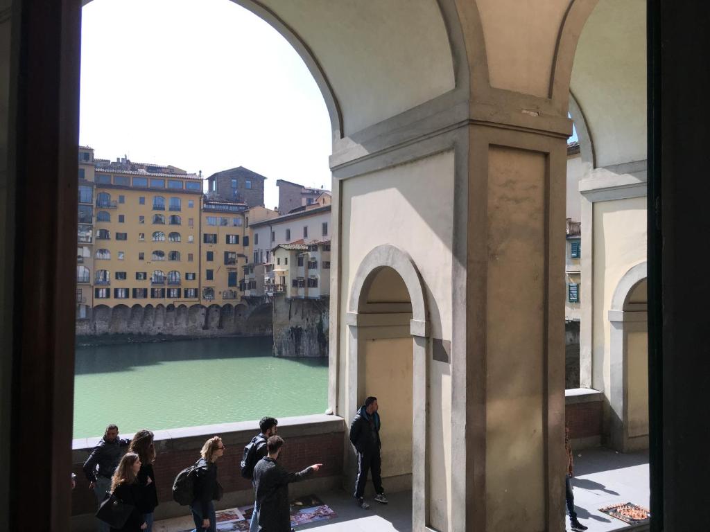 a group of people looking out of a window at a river at La Tana Dei Leoni Affittacamere in Florence