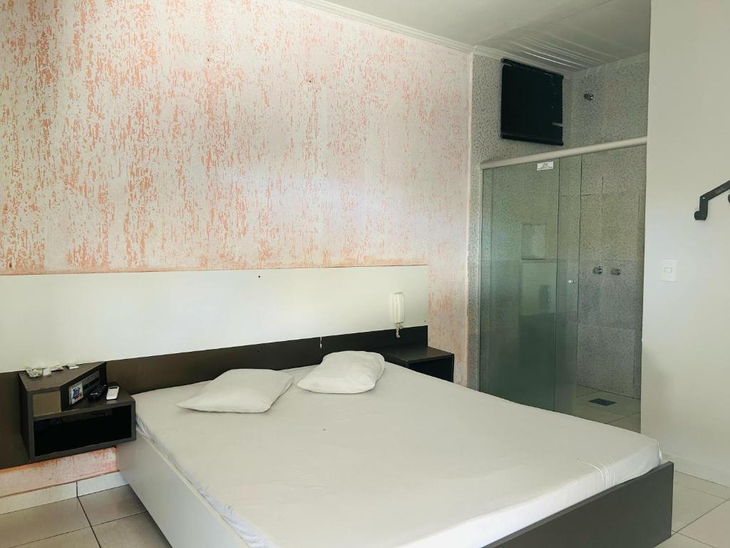 a bedroom with a white bed with two white pillows at Motel Wish in Campinas