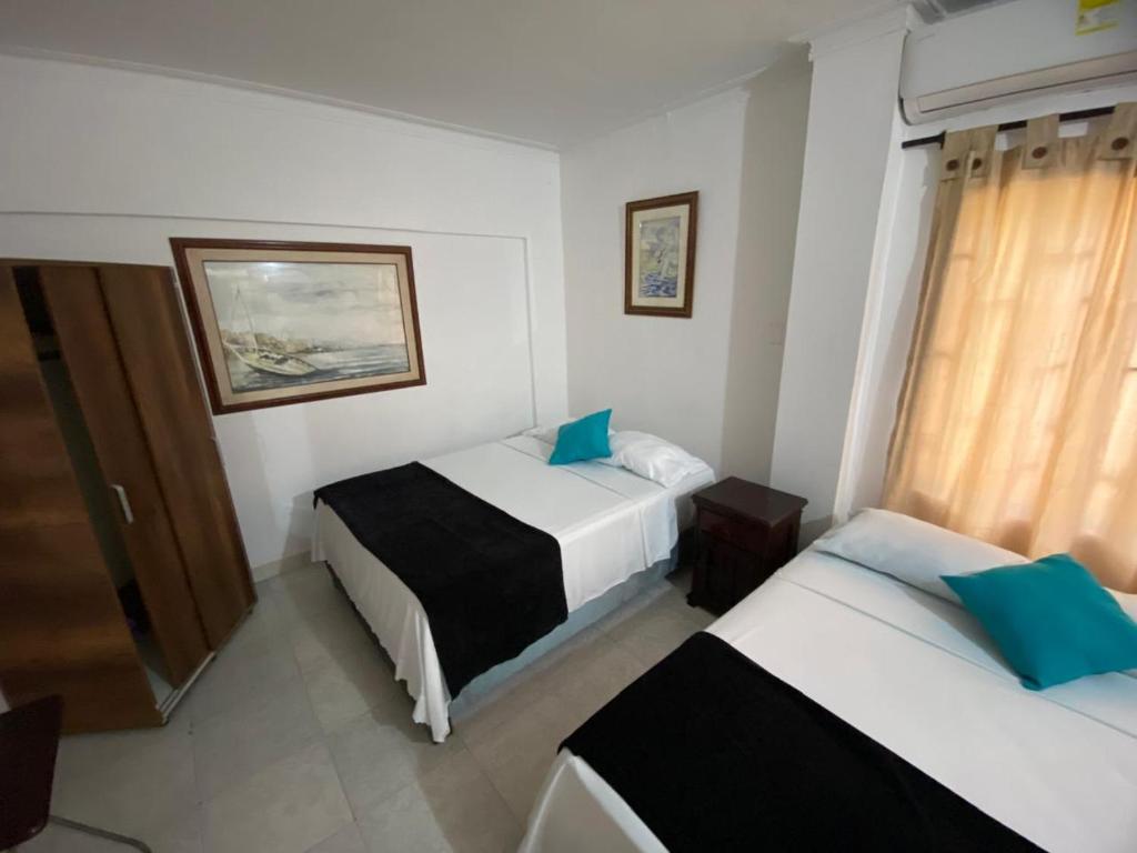 une chambre d'hôtel avec deux lits et une fenêtre dans l'établissement Paraíso en Bocagrande habitaciones, à Carthagène des Indes
