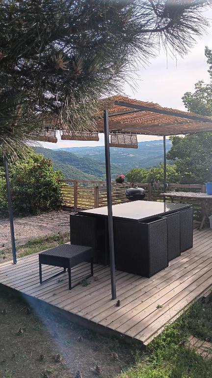 ein Picknicktisch mit Sonnenschirm und einer Bank auf einer Terrasse in der Unterkunft Le grand gîte in Saint-Beauzély