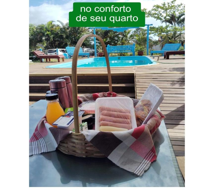 een picknickmand op een tafel naast een zwembad bij Pousada Horizontes do Rosa in Praia do Rosa
