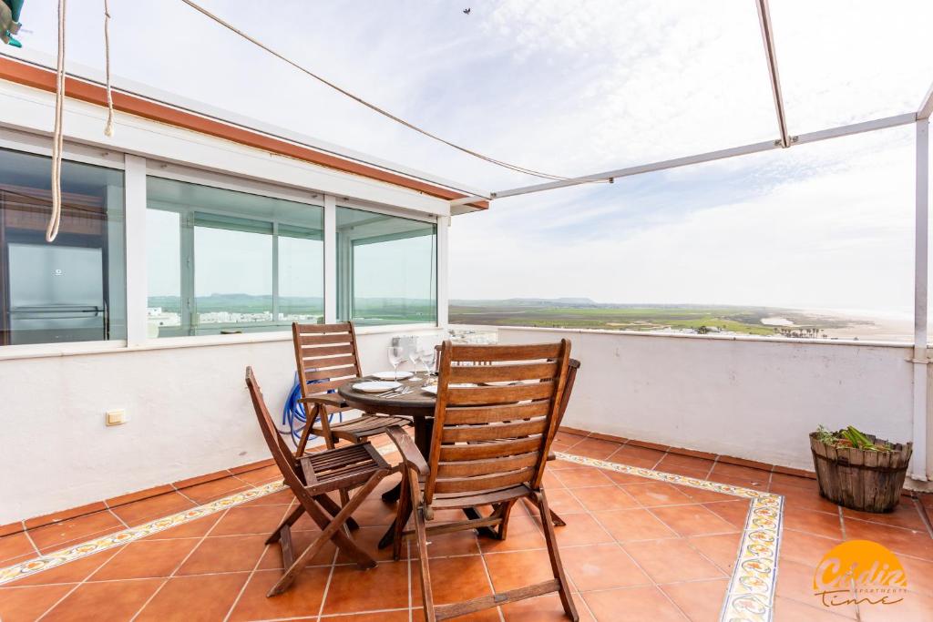 a dining room with a table and chairs on a balcony at Apartamentos Arenal by Cádiz Time in Conil de la Frontera