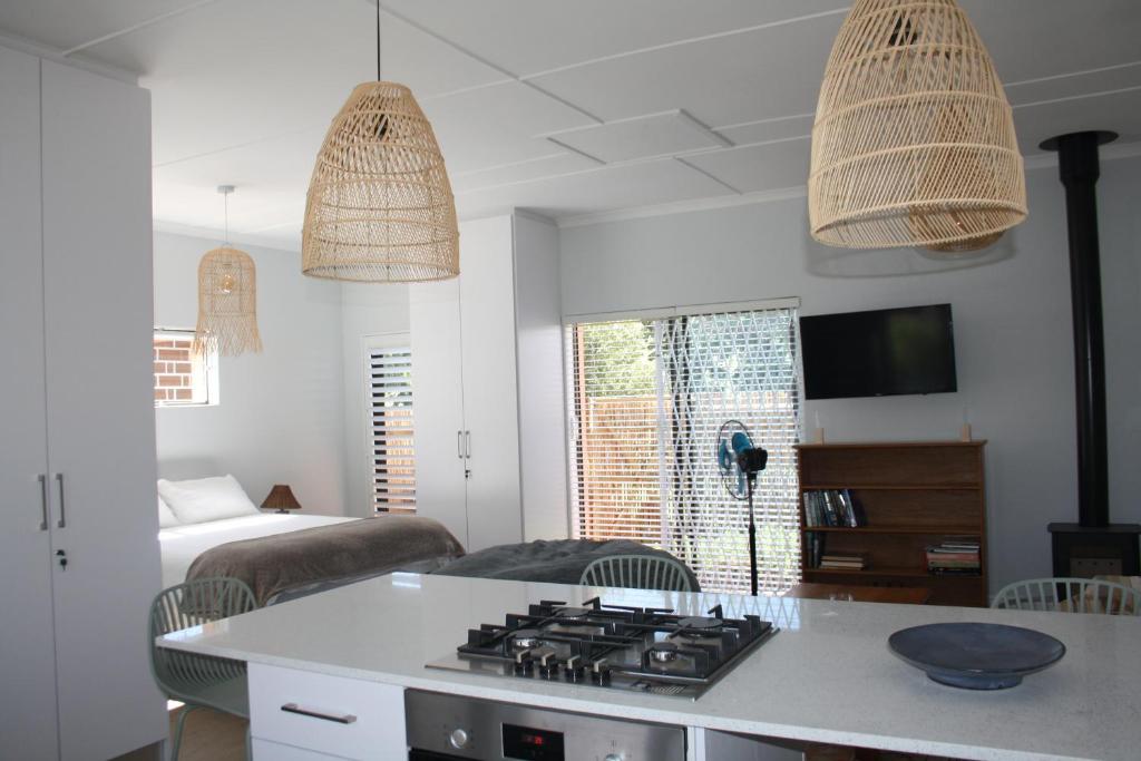 a living room with a kitchen with a stove top at Happy's Hood in Pringle Bay