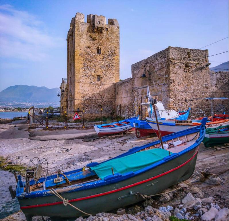 un gruppo di barche sedute sulla spiaggia di fronte a un castello di Renda36 a Carini