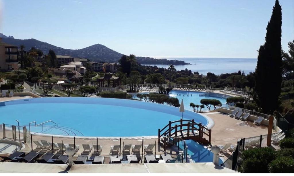 une grande piscine avec des chaises et l'océan dans l'établissement Superbe duplex T3 climatisé avec Terrasse et Solarium, magnifique vue Mer et Golf, à Saint-Raphaël