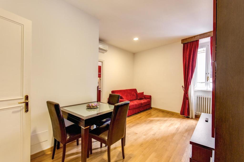 ローマにあるアポロ アパートメンツ コロッセオのリビングルーム(テーブル、赤いソファ付)