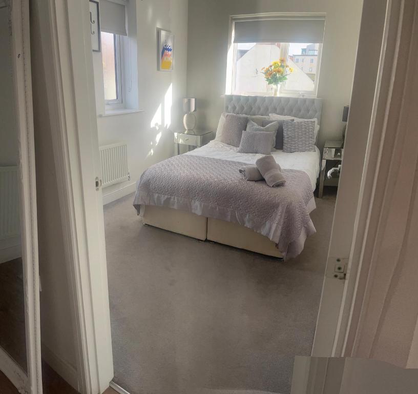 a white bedroom with a bed with a window at Luxury Riverside 2 bedroomed Apartment with Balcony in Newport