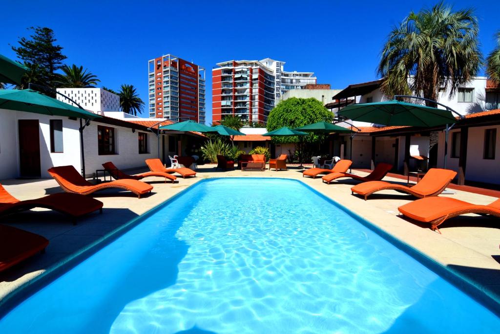 una piscina con tumbonas y sombrillas naranjas en Hotel Concorde, en Punta del Este