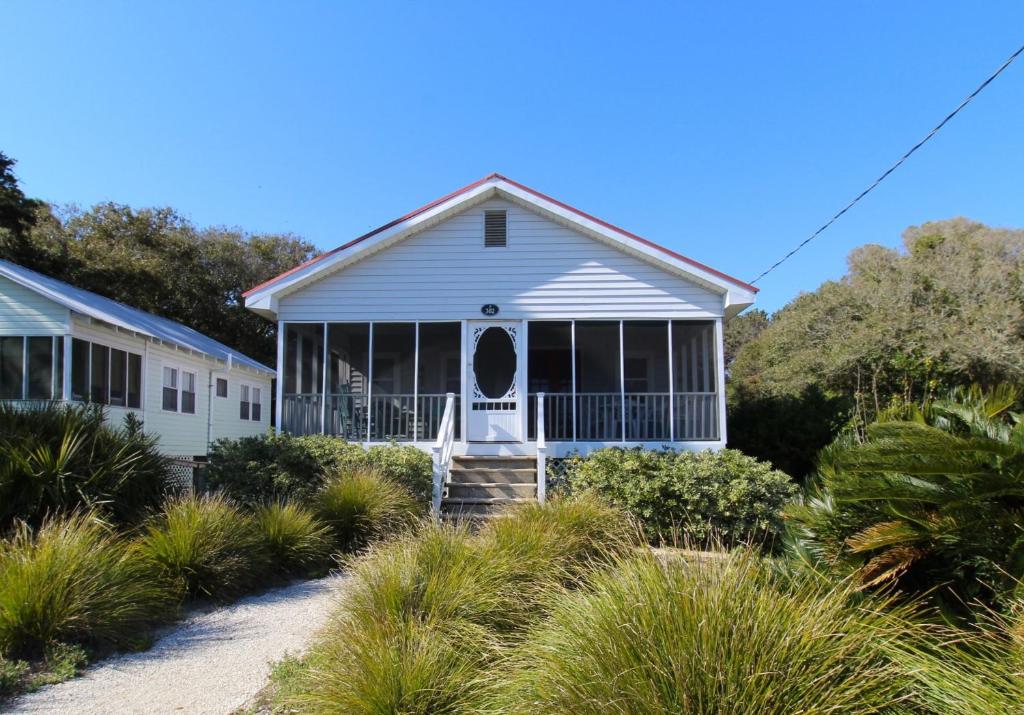 ein weißes Haus mit einer Veranda und Büschen in der Unterkunft Bonnie Dune in Folly Beach