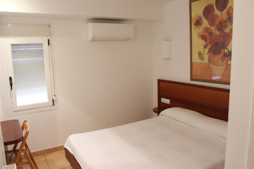 een kleine slaapkamer met een bed en een raam bij Hostal Cristina in Cadaqués