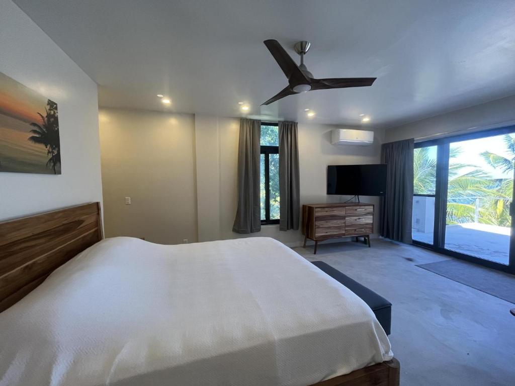 une chambre avec un lit et un ventilateur de plafond dans l'établissement Mayatai Beach Villa - Elegant 2BR Beachfront with Stunning Ocean Views, à Placencia