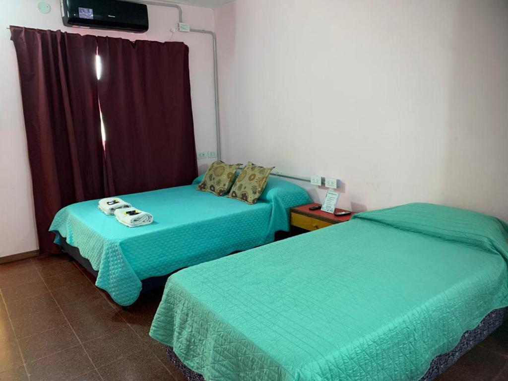 zwei Betten in einem Zimmer mit grüner Bettwäsche in der Unterkunft MDF hospedaje in Villa Mercedes