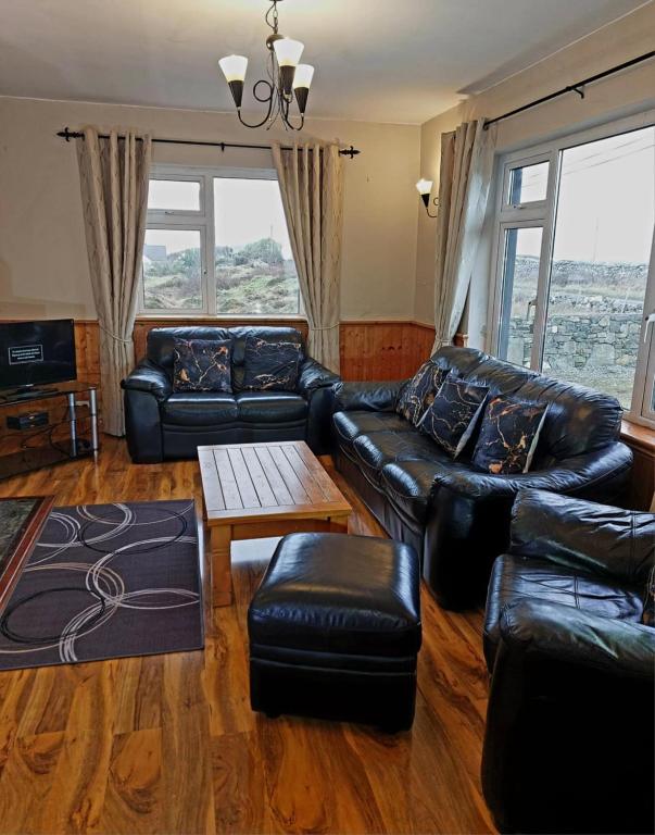 a living room with black leather couches and a table at Kings in Ballyconneely