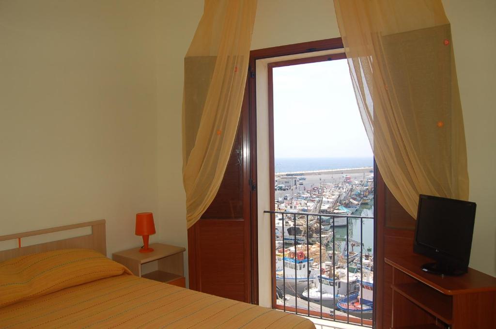 a bedroom with a bed and a balcony with a view at Le Casette del Porto di Sciacca in Sciacca