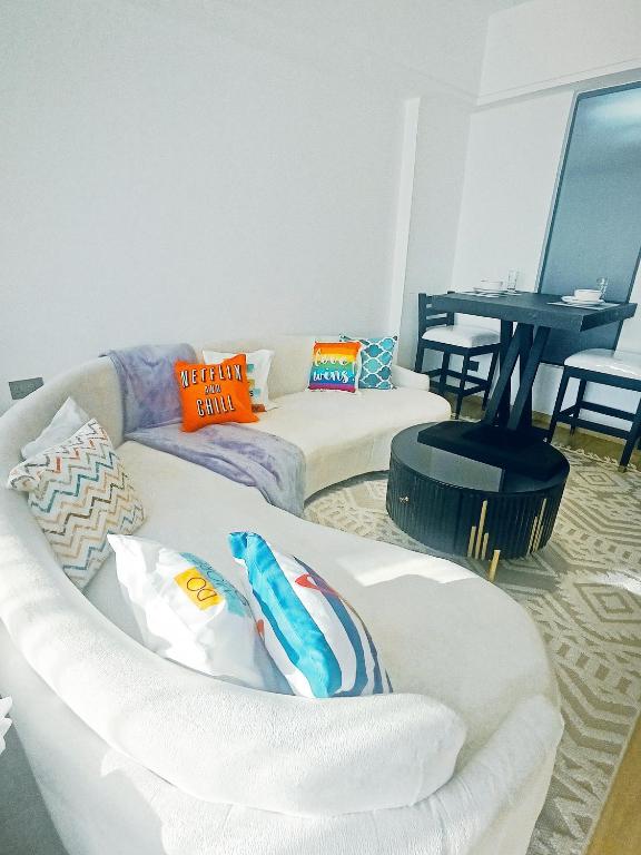 a living room with two white couches and a table at Eika - Refined and luxurious studio Apartment in Nairobi