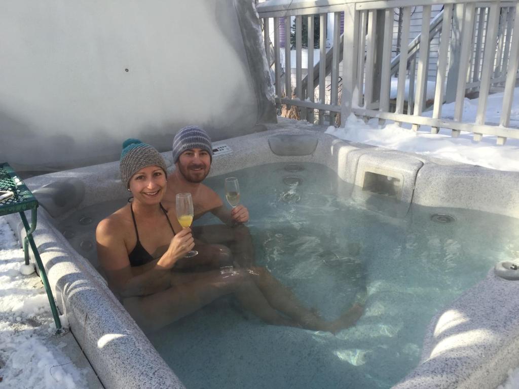 un hombre y una mujer sentados en un jacuzzi con una copa de vino en Phineas Swann Inn & Spa, en Montgomery Center