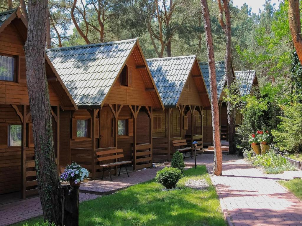 a row of wooden cabins in a forest at Cottage in azy near Beach and Lake Jamno in Łazy