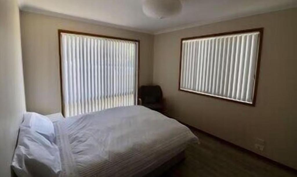 a bedroom with a white bed and two windows at 36 Betka Road in Mallacoota