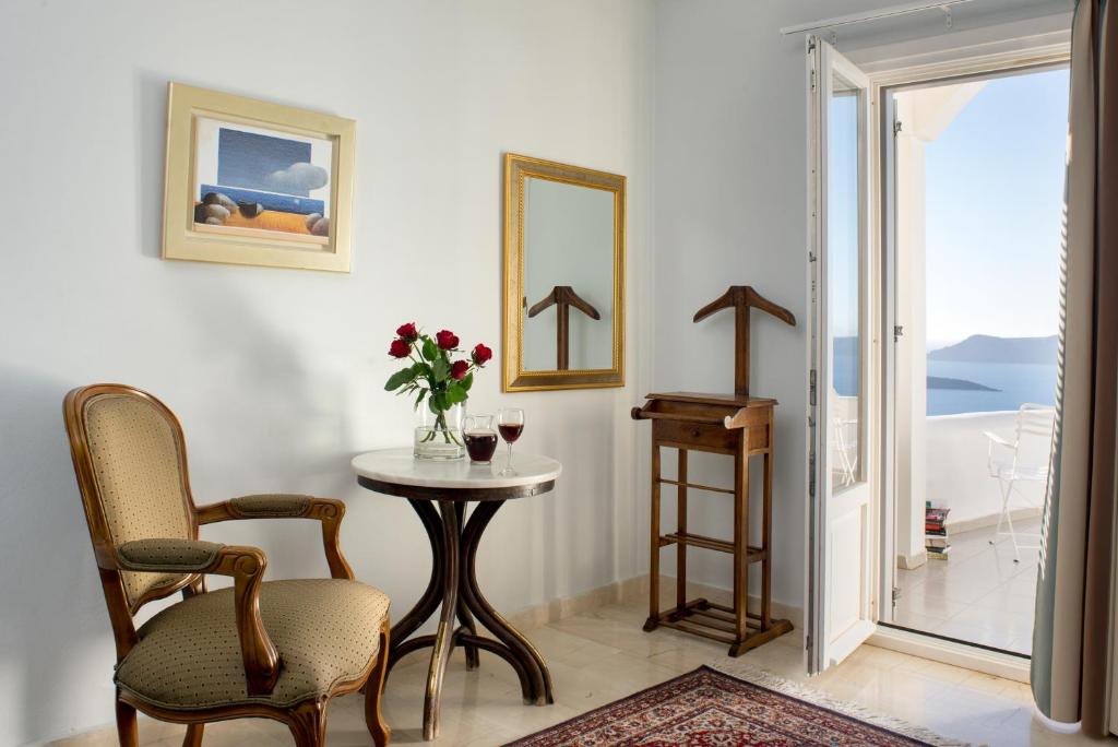 a room with a table and two chairs and a mirror at Villa Renos Hotel in Fira