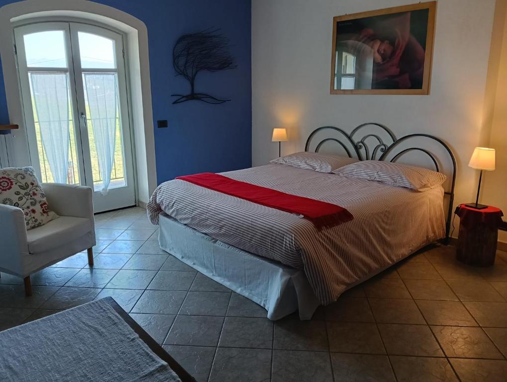 a bedroom with a large bed and a chair at Casa Arcobaleno Holiday home apartments in Diano dʼAlba