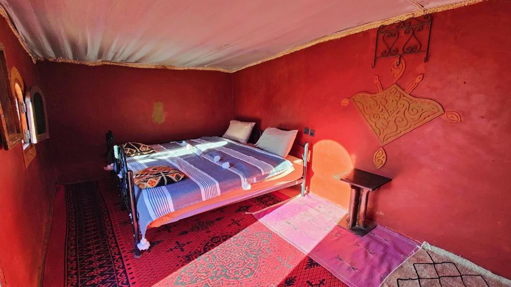 una camera con un letto in una stanza rossa di Nomads Heaven Camp a M'Hamid