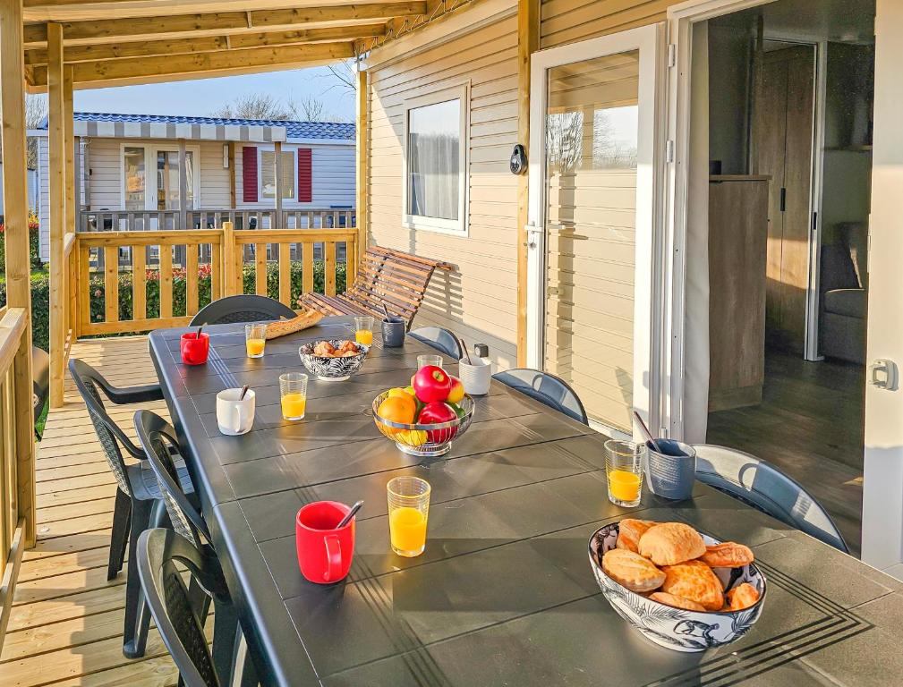 a table with bowls of bread and fruit on a porch at La Sérénité Normande in Litteau