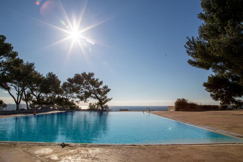 une piscine bleue avec le soleil dans le ciel dans l'établissement Cadre exceptionnel - Appt Classé 3 entièrement climatisé - Mer-piscine-tennis, à Bandol