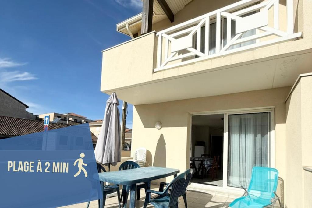 un patio avec une table et des chaises devant une maison dans l'établissement Douceur Océane Terrasse & Balcon, à Mimizan-Plage