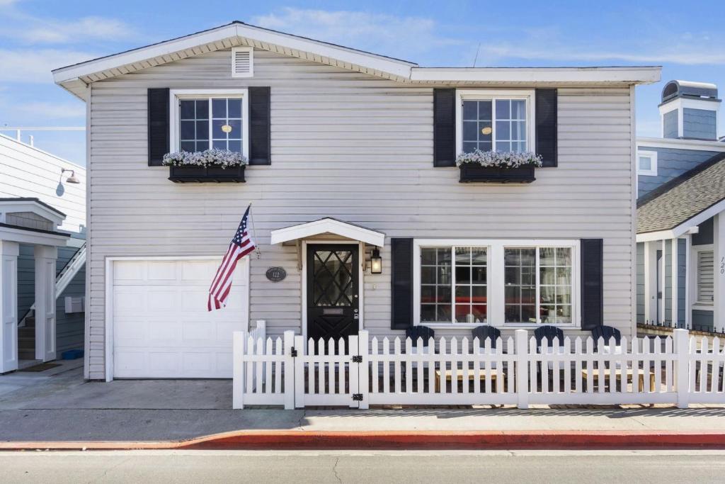 a white house with a fence and an american flag at 122 Thirty Third Street in Newport Beach