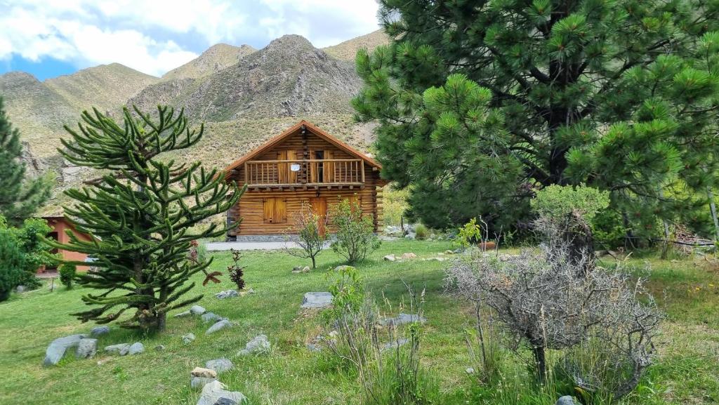 a log cabin in a field with mountains in the background at La Araucaria in Potrerillos