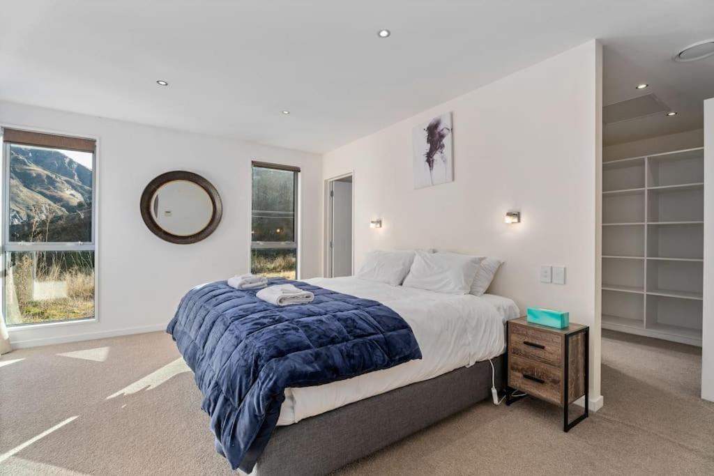 ein Schlafzimmer mit einem großen Bett und einem Spiegel in der Unterkunft Huge &amp; Stylish on Shotover 4 Bedrooms in Queenstown