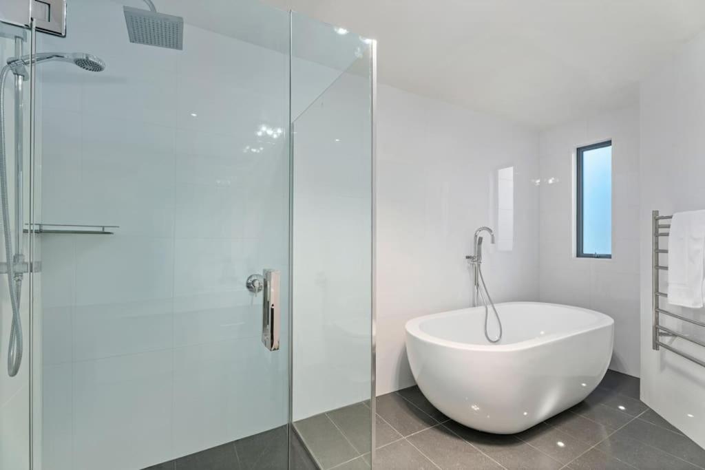 ein Badezimmer mit Badewanne und Glasdusche in der Unterkunft Huge &amp; Stylish on Shotover 4 Bedrooms in Queenstown