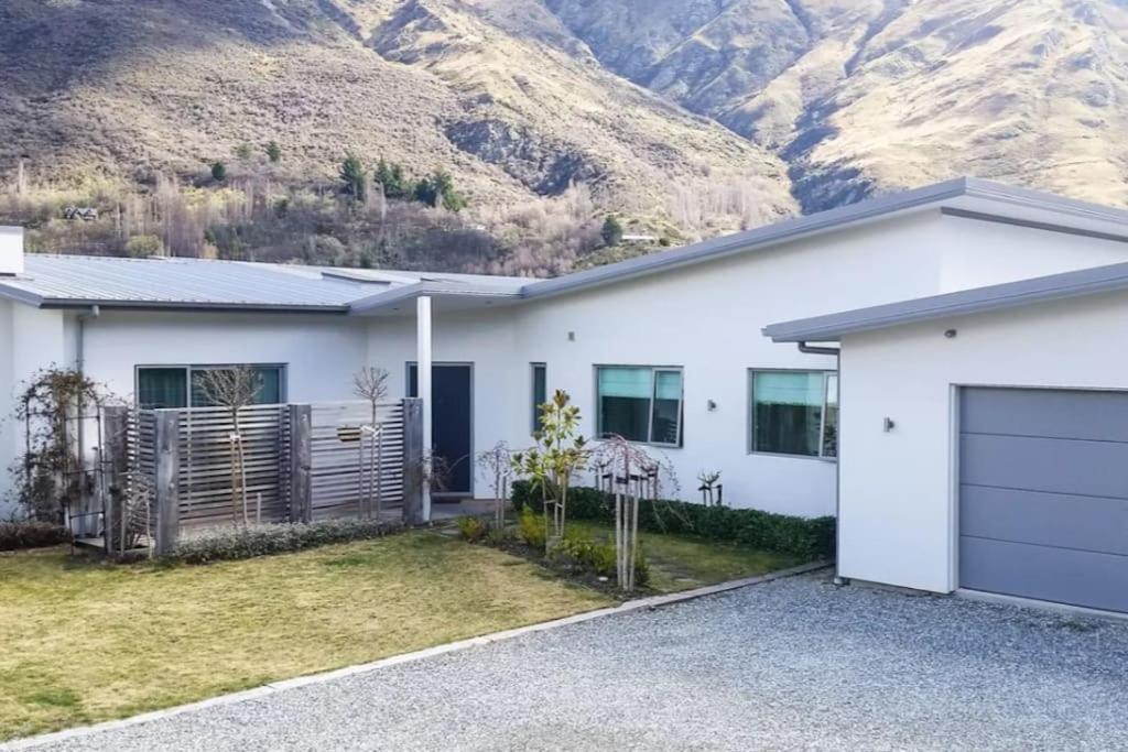 ein weißes Haus mit einem Berg im Hintergrund in der Unterkunft Huge &amp; Stylish on Shotover 4 Bedrooms in Queenstown