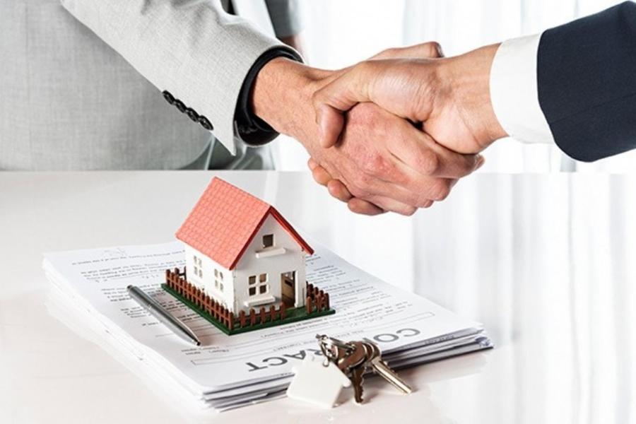 a couple shaking hands over a paper with a house on it at Estadia in São Luís