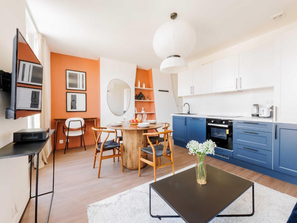 une cuisine et une salle à manger avec des armoires bleues et une table dans l'établissement Cosy Apartment Le Bon Marche, à Paris