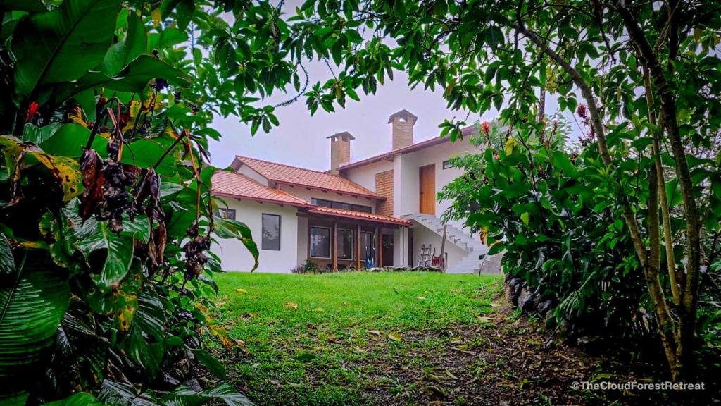 a house with a yard with trees in front of it at The Cloud Forest Retreat in Pelagallo