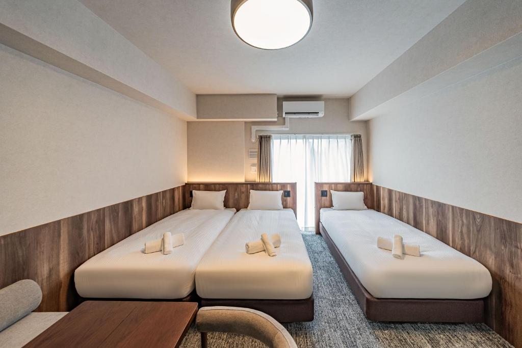 a hotel room with two beds and a table at Apartment Hotel 11 Kuromon 4 in Osaka