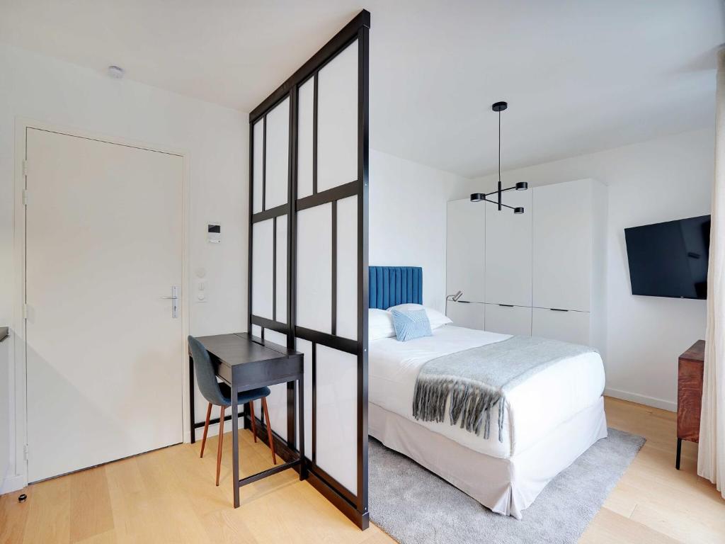 une chambre avec un lit, un bureau et un miroir dans l'établissement Studio Sleek & Refined - Levallois-Perret, à Levallois-Perret