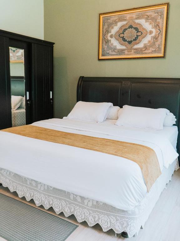 a bedroom with a large bed with white sheets at TM 16 Padang - Mentawai Tour Package, Airport Transport, Sumatra Local Touch in Padang