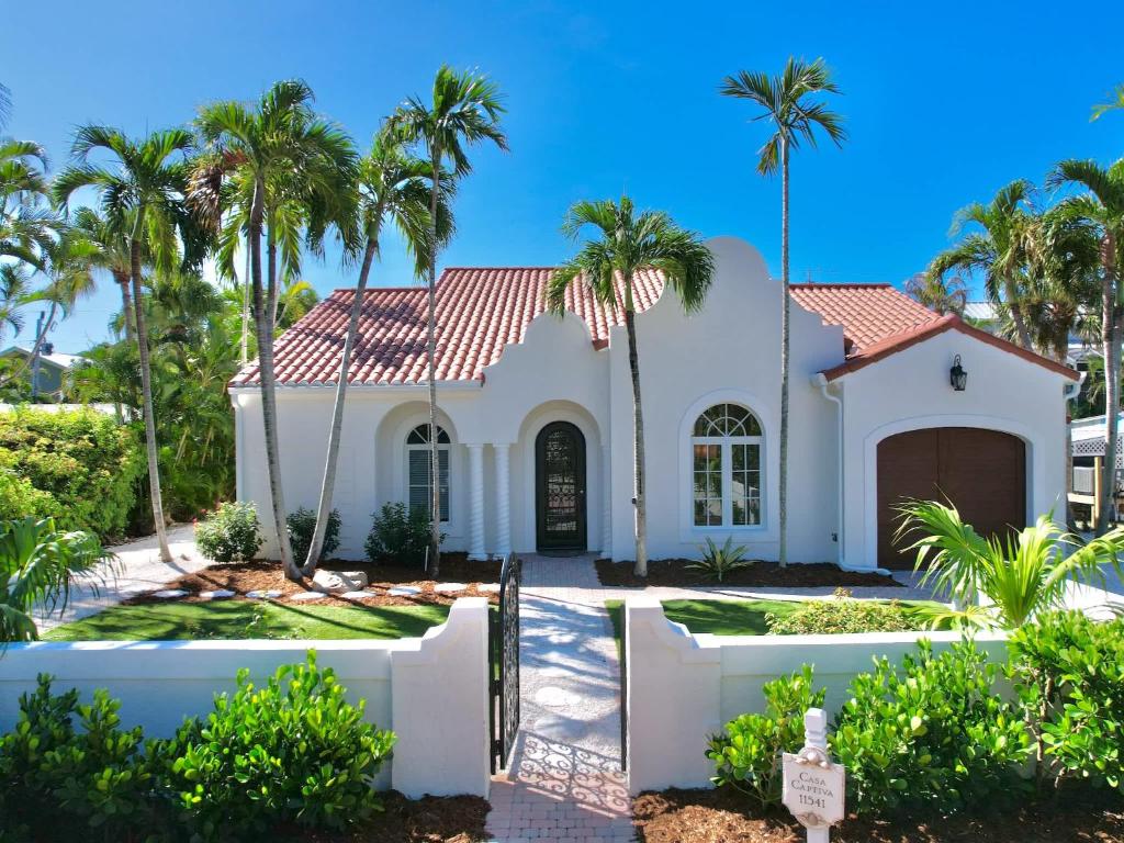 a white house with palm trees in front of it at Casa Captiva - Deluxe 5 Bedroom Villa Steps to Beach in Captiva