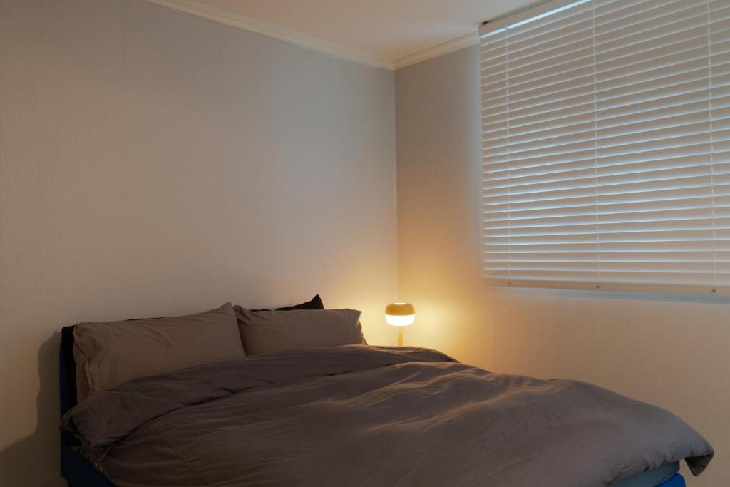 a bedroom with a bed with a lamp and a window at Manoa Garden in Seoul