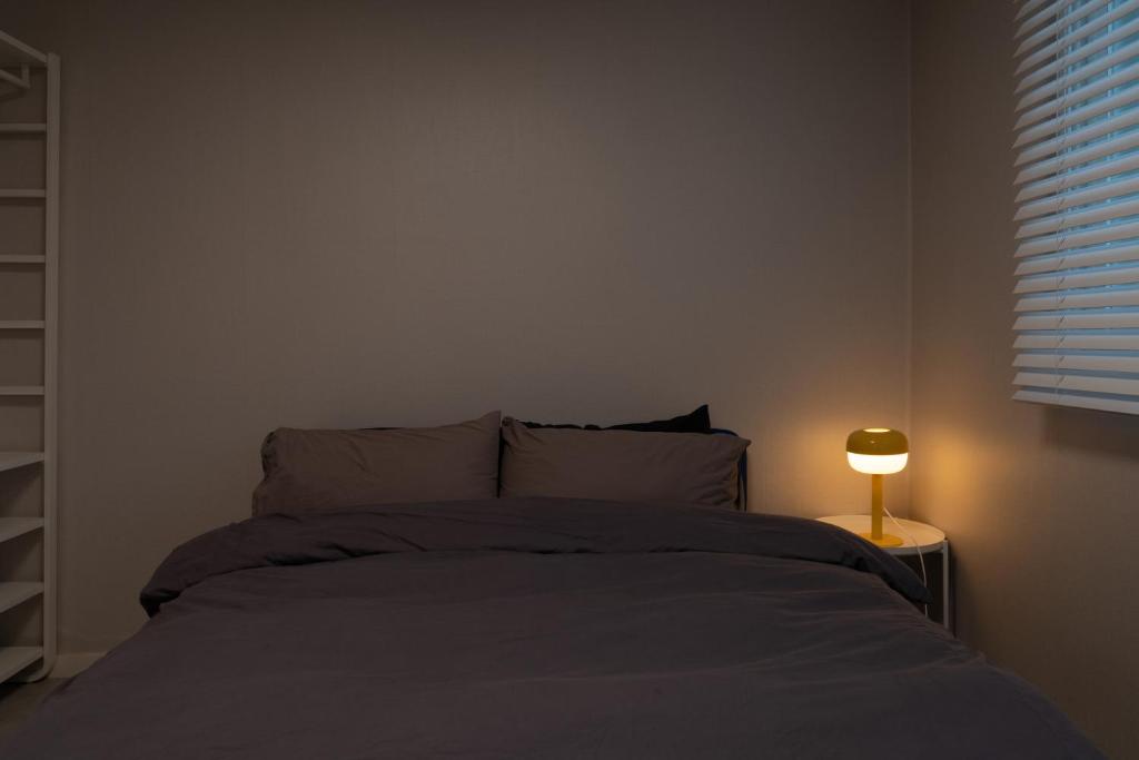 a bedroom with a bed and a lamp on a table at Manoa Garden in Seoul