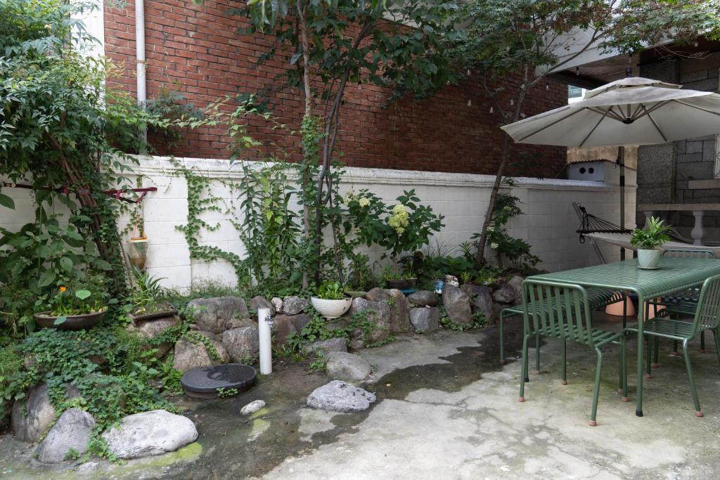 a table and chair with an umbrella in a garden at Manoa Garden in Seoul